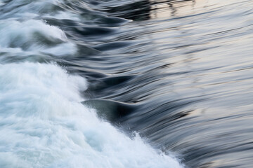 Rapid water flow over barrier with silky surface, river overflow over dam close up with splash and...