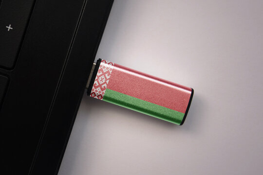 usb flash drive in notebook computer with the national flag of belarus on gray background.