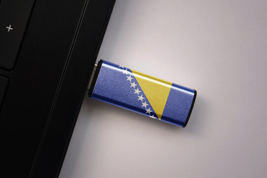 usb flash drive in notebook computer with the national flag of bosnia and herzegovina on gray background.