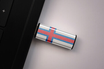 usb flash drive in notebook computer with the national flag of faroe islands on gray background.