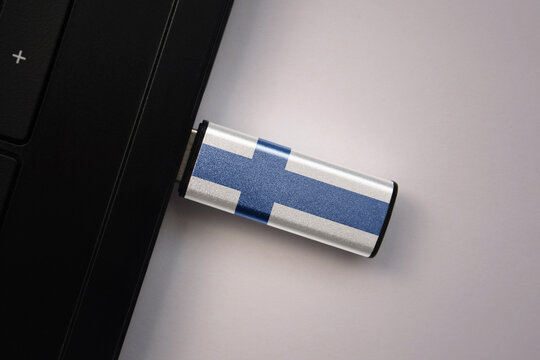 usb flash drive in notebook computer with the national flag of finland on gray background.