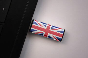 usb flash drive in notebook computer with the national flag of great britain on gray background. concept