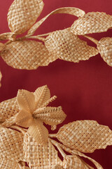 Fototapeta na wymiar Branch with leaves and flowers is made of straw. Decoration of straw on a red background. Decor. Fragment closeup