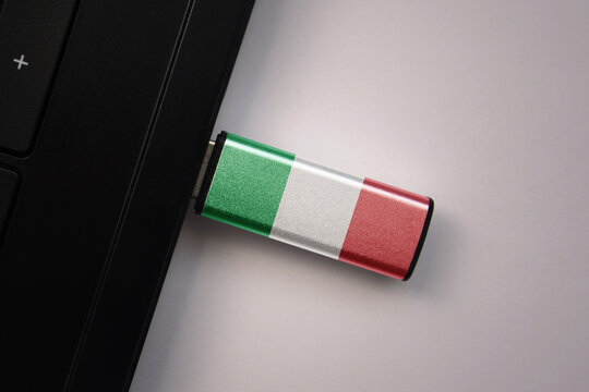 usb flash drive in notebook computer with the national flag of italy on gray background.