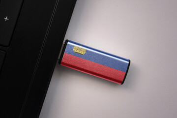 usb flash drive in notebook computer with the national flag of liechtenstein on gray background.