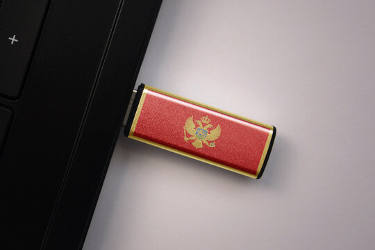 usb flash drive in notebook computer with the national flag of montenegro on gray background.