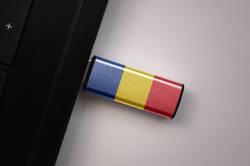 usb flash drive in notebook computer with the national flag of romania on gray background.