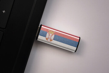 usb flash drive in notebook computer with the national flag of serbia on gray background.