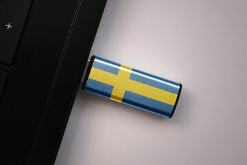 usb flash drive in notebook computer with the national flag of sweden on gray background.