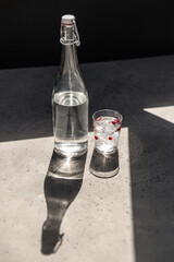objects and drinks concept - bottle of water and glass with ice and cranberries on sunny floor - 755862303