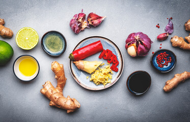 Food and cooking background with fresh raw vegetables. Gray table with paprika, zucchini, spices and ingredients for cooking Asian dishes with ginger, garlic, soy sauce and lime, top view
