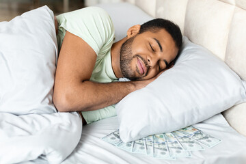 Black man sleeping with bunch of cash dollars under pillow