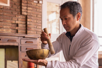 Asian Man Playing a Tibetan Singing Bowl