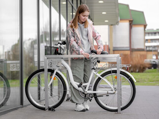 Girl Fastens Bike Near Supermarket Bike Parking In Spring - 755875955