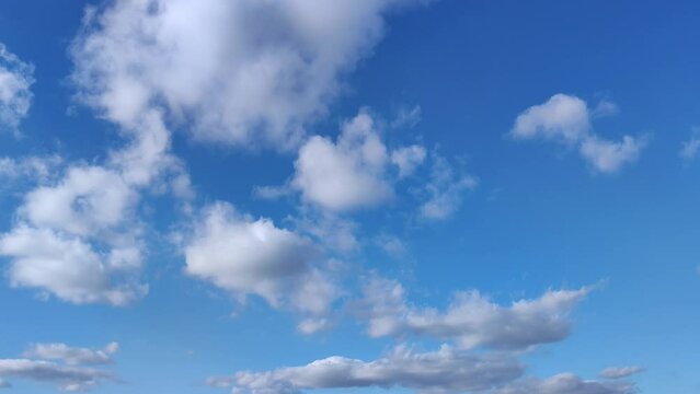 Small clusters of clouds move across the clear blue sky