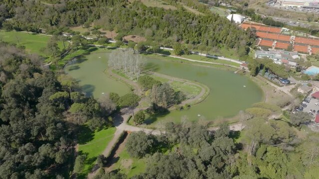 Aerial view of the small lake of Villa Ada, a public park in Rome, Italy. In the center of the lake there is a small island with trees and a green area.