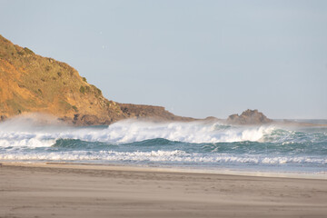 sunset at sandfly bay in new zealand in spring with wind and waves