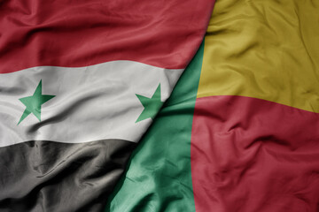 big waving national colorful flag of benin and national flag of syria .