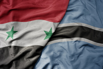 big waving national colorful flag of botswana and national flag of syria .