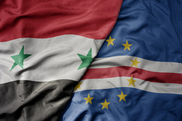 big waving national colorful flag of cape verde and national flag of syria .
