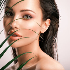 Young beautiful woman with green leaves near face.  White model with clean, health skin of face. - 755889382