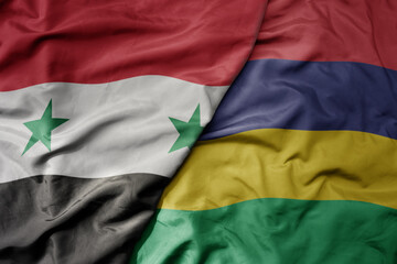 big waving national colorful flag of mauritius and national flag of syria .