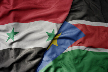 big waving national colorful flag of south sudan and national flag of syria .