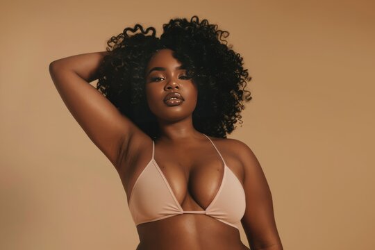 Confident full-body shot of a beautiful black woman, embracing body positivity, on a beige background