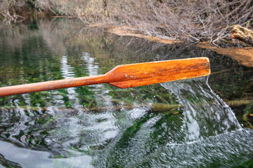 Closeup of oar paddle from row boat moving in water on green lake with ripples - 755895958