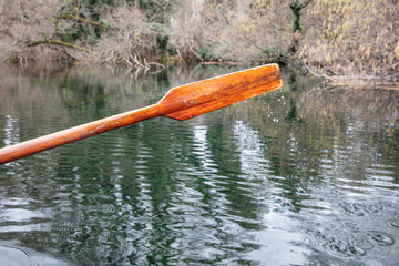 Closeup of oar paddle from row boat moving in water on green lake with ripples - 755895997