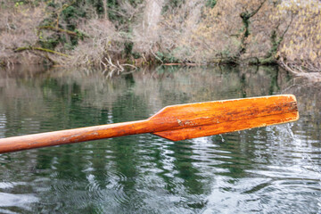 Closeup of oar paddle from row boat moving in water on green lake with ripples - 755896121