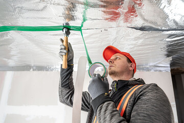 The builder is gluing the special tape on the joint of vapor barriers.  The vapor barrier as...