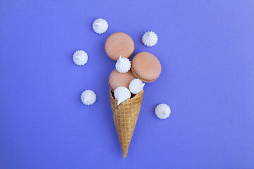 Ice cream cone with chocolate macaron and white meringue on the purple background. Top view.