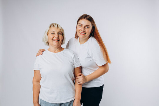 Head shot portrait of happy senior 60s mother and young grownup daughter over white studio background. Happy joyful family