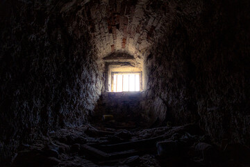 Licht und Sonnenstrahlen fallen durch ein kleines weit entferntes vergittertes Kellerfenster