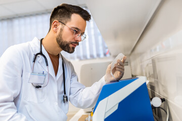 Male veterinarian working in laboratory. Vet doctor is examining sample at animal hospital. He is...