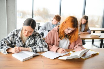 Testing. Closeup of young students sitting in a row and having test in their test-books