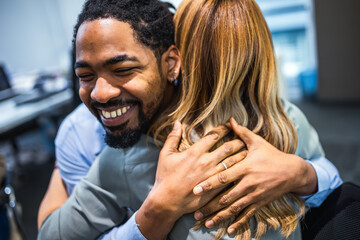 Multiethnic group of coworkers hugging at a group therapy session, overcoming problem together.