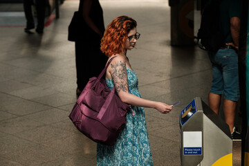 A caucasian woman is holding a card on a transport reader.