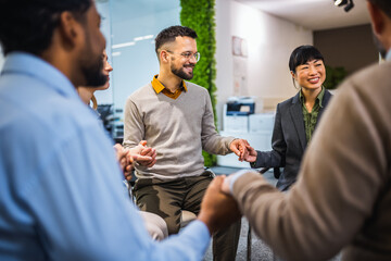 Fototapeta premium Group of people sitting in a circle holding hands and participate in a support meeting. Healthcare and medicine concept.