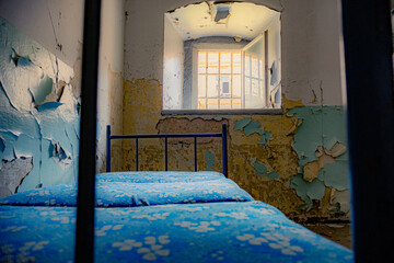 Gefängnisbett mit blauen Matratzen in einer Gefängniszelle in einem verlassenen Gefängnis