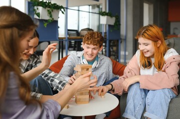Group of creative friends sitting at wooden table. People having fun while playing board game © Serhii