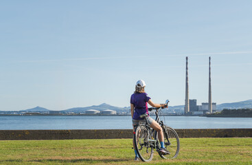 Fototapeta premium Cyclist woman enjoys her adventures and the landscape of the Dublin chimneys and the mountains