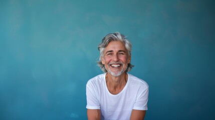 Fototapeta premium A middle-aged man with gray hair on a blue background with a pleasant smile. Health and beauty, healthy teeth.