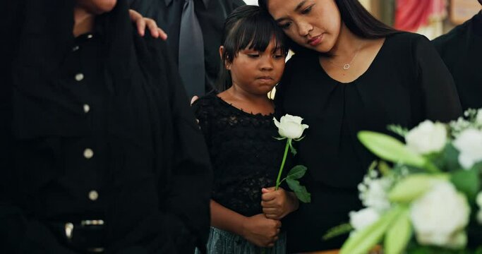 Funeral, family and woman with child at coffin with flower at memorial service at church in respect, support and comfort. Death, grief and widow with daughter, rose and goodbye at casket for farewell