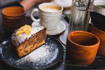 A piece of homemade cake and coffee. Breakfast in a cafe on the street.