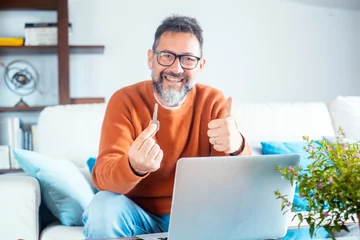 Fotobehang One cheerful adult man showing new hone ket and thumb up smiling at the camera. Finding house apartment online on website concept. Searching property on web. Business real estate people and notebook © simona