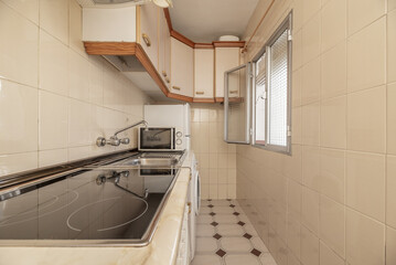 A small kitchen furnished with furniture on a single wall, with an old ceramic hob and an open...