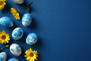Blue and white Easter eggs with yellow flowers on dark blue background. Happy Easter concept
