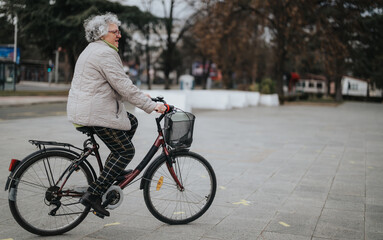 Obraz premium Mature woman enjoying a leisurely bike ride in a serene city park environment.